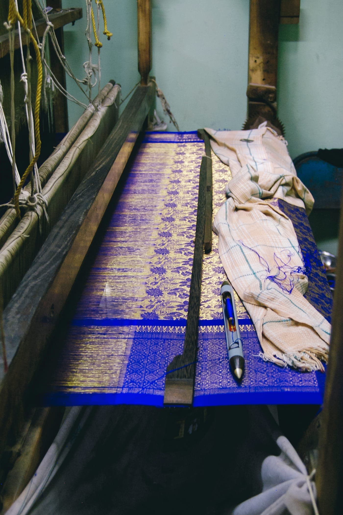A blue and gold saree being woven on a loom